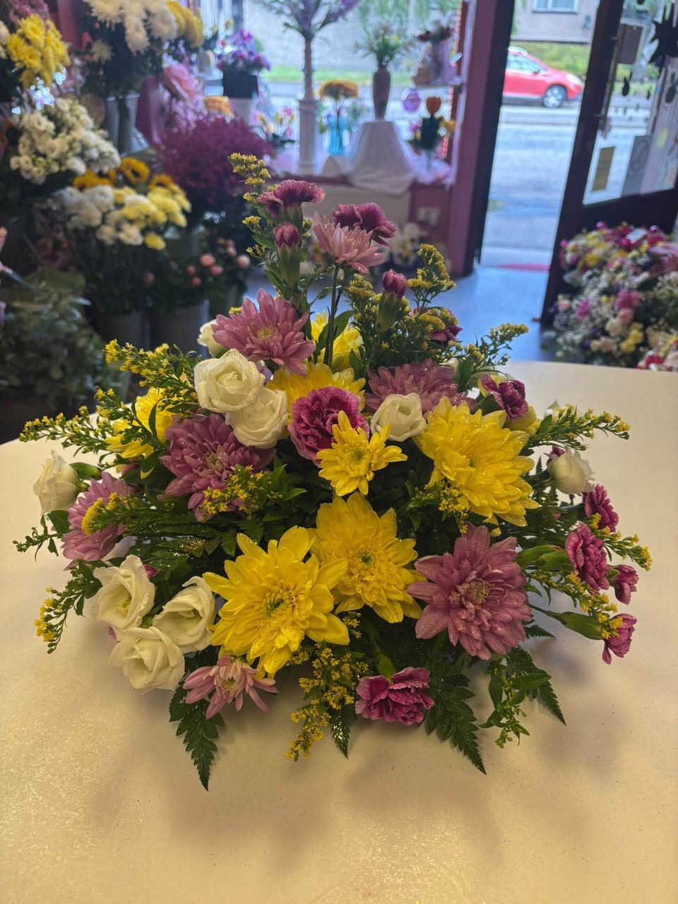 Arrangement of yellow chrysanthemums, pink carnations and cream roses