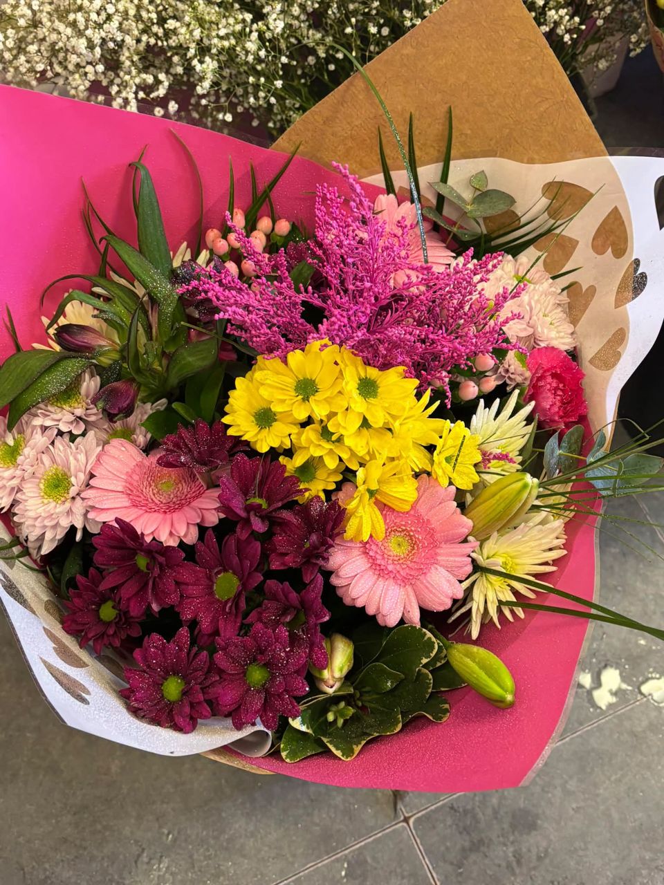Hand tied bouquet of pink gerberas, yellow chrysanthemums and lilies in pink wrap